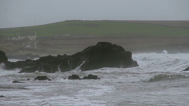 当海浪拍打海岸时，暴风雨的波浪拍打着巨大的岩石视频素材