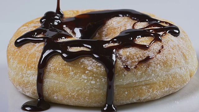 美味的融化巧克力糖浆倒在甜甜圈上视频素材
