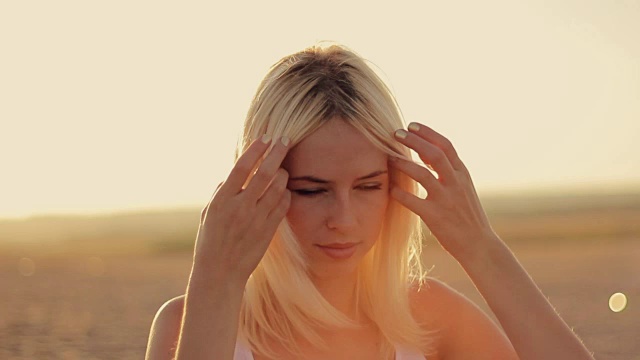 性感的年轻女子近距离在日落太阳纠正长白发和呼吸新鲜空气视频下载