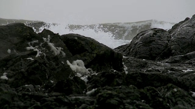 当海浪拍打海岸时，暴风雨的波浪拍打着巨大的岩石视频素材