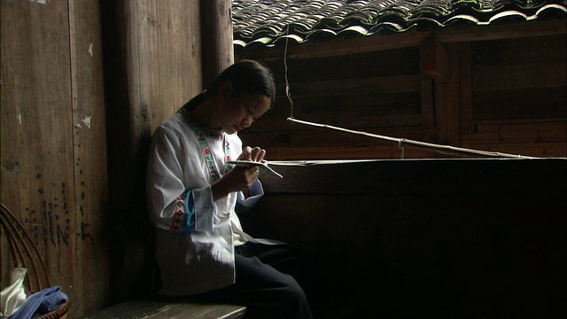 广西桂林平安村，壮族姑娘坐在长凳上做针线活视频下载