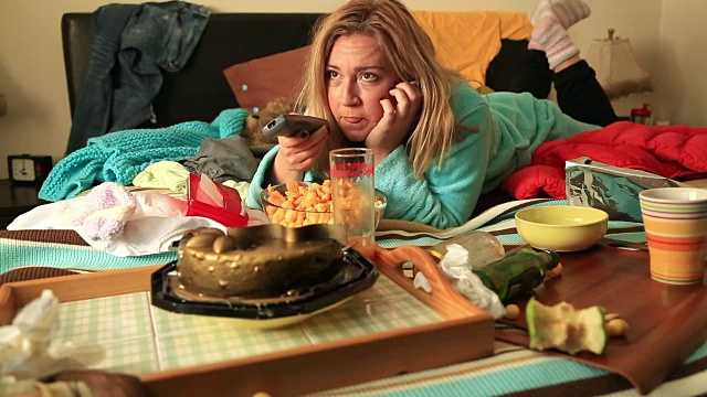 抑郁的女人一边吃一边看电视视频素材