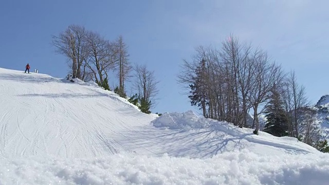 慢镜头特写:滑雪者在一个美丽的阳光明媚的一天在滑雪场滑雪场跳过镜头视频素材