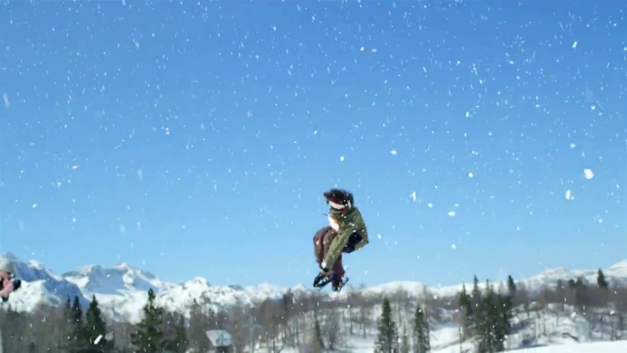 慢镜头特写:自由式滑雪者跳跃大kicker和飞越在雪山的太阳视频购买