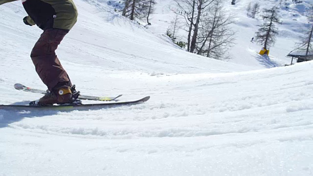 慢镜头特写:自由式滑雪者滑雪超过踢球和跳跃在阳光灿烂的雪园视频素材