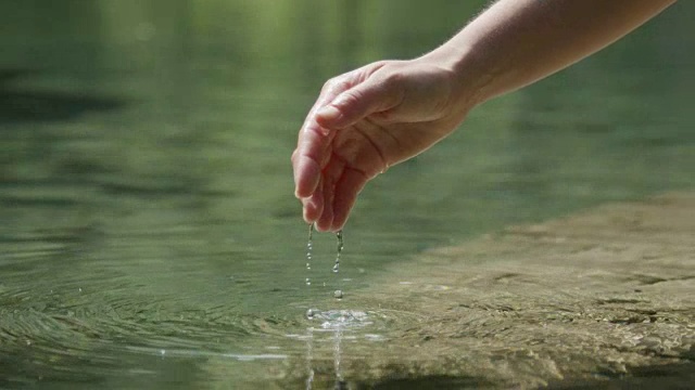 慢镜头特写:手握着，把新鲜的水倒进美丽的山泉湖中视频素材