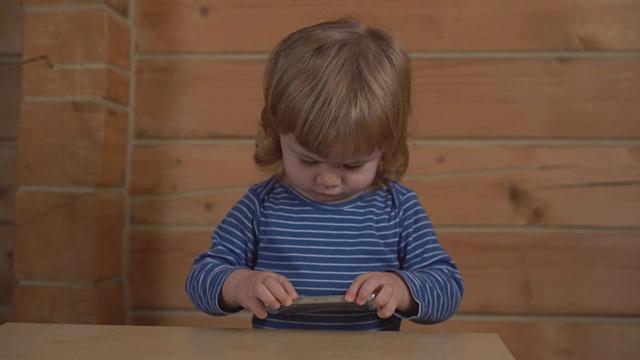 小卷毛宝宝在木屋里看手机视频素材