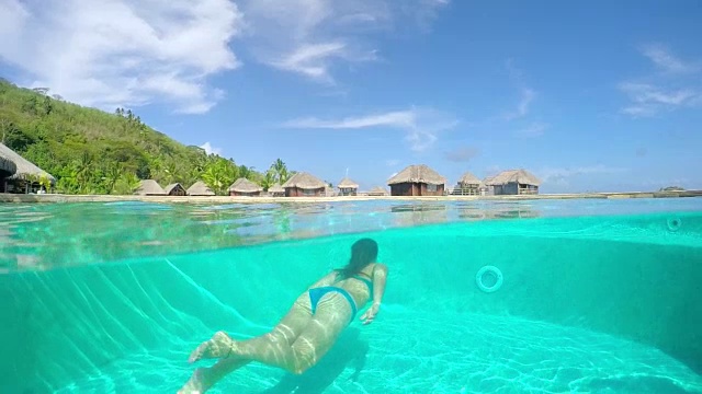 水下:女子在游泳池中向豪华度假别墅跳水视频素材