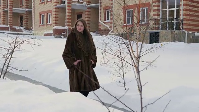 穿着皮大衣穿过冬村的女孩视频素材