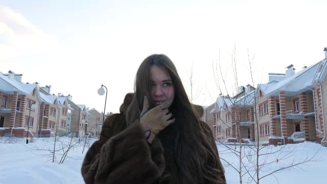 穿着皮大衣的女孩在冬村散步视频素材
