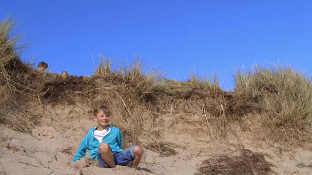男孩从沙丘上跳下来的慢动作镜头视频素材