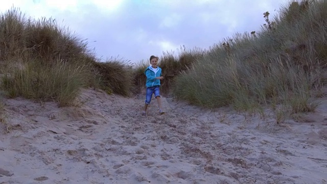 男孩跑过沙丘的慢动作镜头视频素材