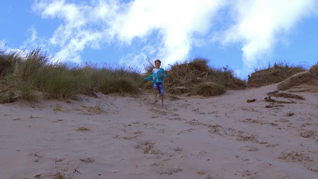 男孩跑过沙丘的慢动作镜头视频素材