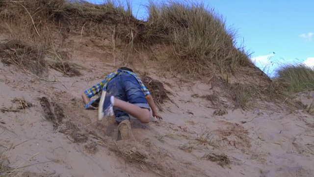 男孩从沙丘上跳下来的慢动作镜头视频素材