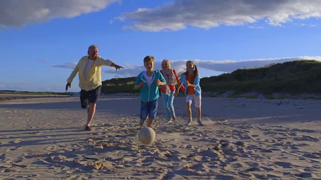 爷爷奶奶在沙滩上和孙子孙女踢足球视频下载