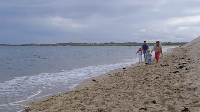 一家人在海边散步，父亲背着女儿的慢镜头视频素材