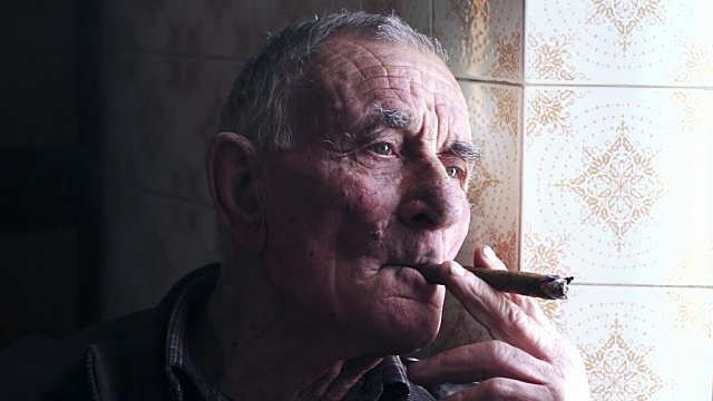 一位老人站在窗前抽雪茄视频素材