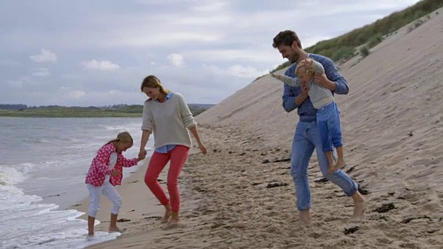 在慢镜头中，一家人带着孩子逃离海浪视频素材