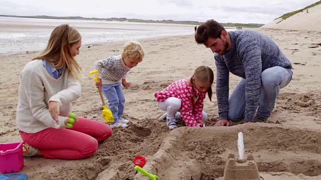 一家人和孩子们一起在海滩上建造沙堡视频下载