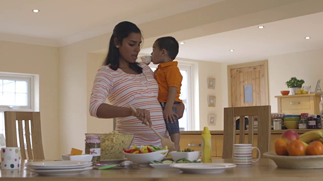 怀孕的母亲在厨房做沙拉的时候怀上了儿子视频素材