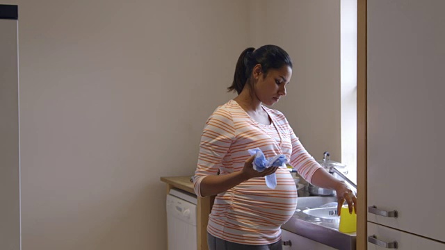 背痛的孕妇在厨房水槽里洗盘子视频素材