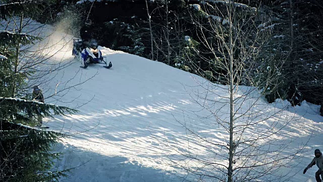 滑雪者，雪地车和滑雪板通过斜坡视频素材