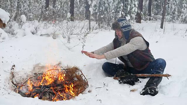 男人在冬季篝火旁暖手视频下载