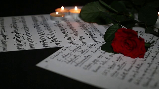三朵美丽的玫瑰，书，音符，玻璃和燃烧的蜡烛视频下载