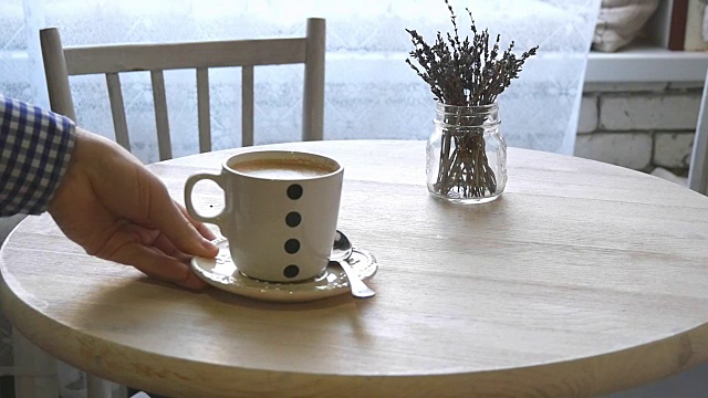 一个男人慢慢地把一杯咖啡放在桌子上视频下载