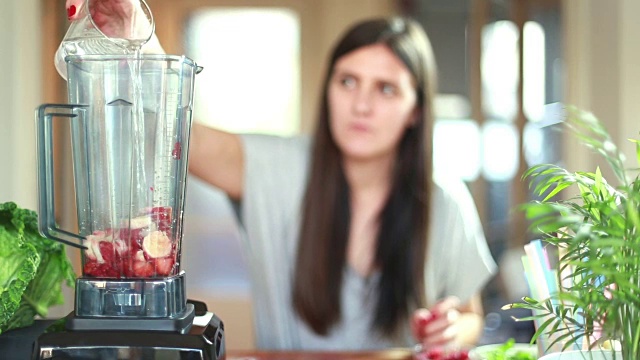 往搅拌机里倒水果的女人视频素材