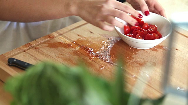 女人用手切樱桃番茄，然后把它们放在白色的碗里视频素材