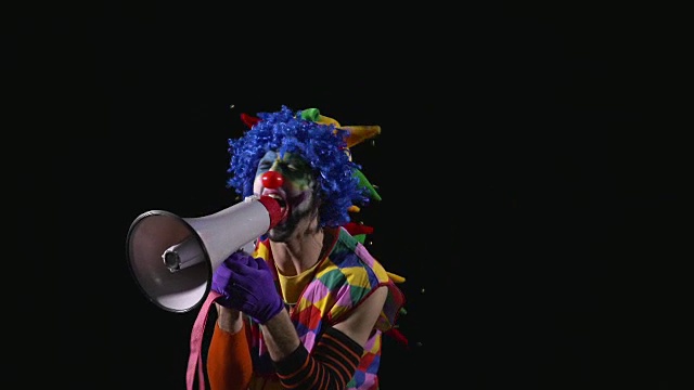 年轻滑稽的小丑用扩音器大喊大叫视频素材