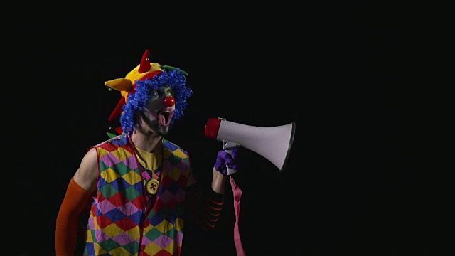 年轻滑稽的小丑用扩音器大喊大叫视频素材