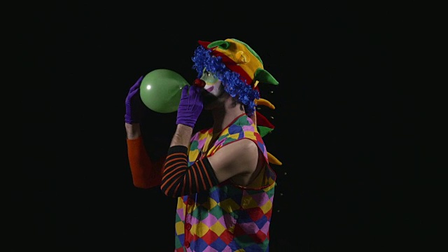 年轻有趣的小丑给气球充气，并让它在鼻子上保持平衡视频素材