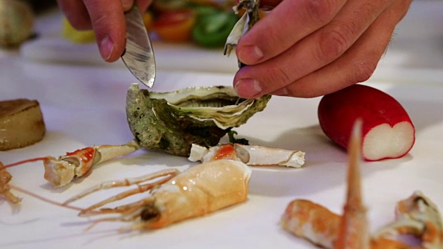一个人用刀剥新鲜的牡蛎，凸轮移到左边，特写视频下载