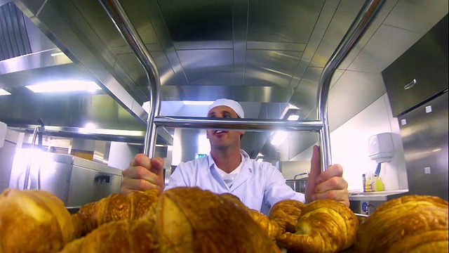 年轻的面包师推着一辆牛角面包车视频素材