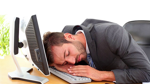 疲惫的商人在他的办公桌上睡觉视频素材