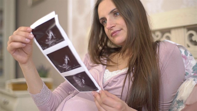年轻孕妇考虑照片3D超声子宫内的婴儿。缓慢的运动。视频下载