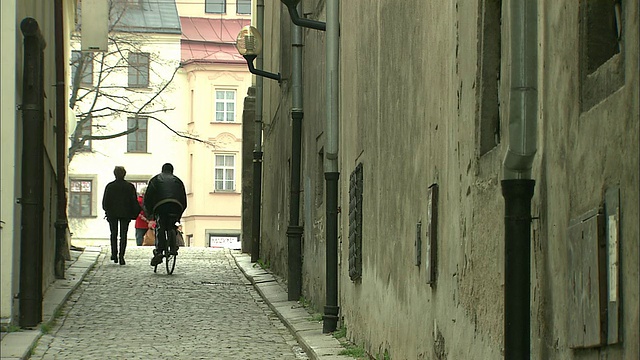 骑自行车的人爬上狭窄的斜坡鹅卵石小巷视频素材