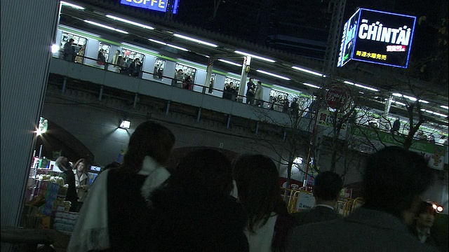 当火车从头顶经过时，通勤者朝火车站走去视频素材