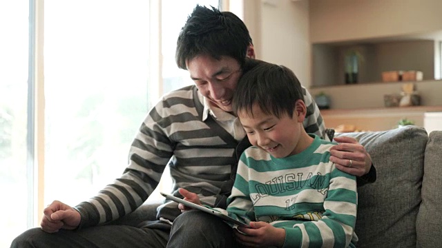 父亲和儿子在家里使用数字平板电脑视频素材