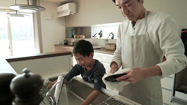 父亲和儿子一起在厨房洗盘子视频素材