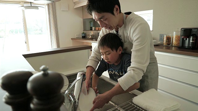 父亲和儿子一起在厨房洗盘子视频素材