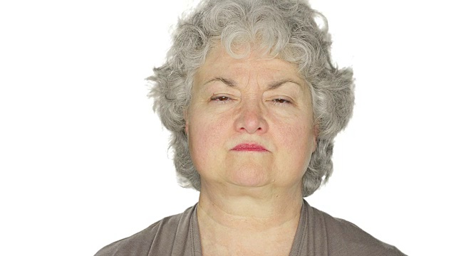 一个成熟的女人生气地盯着一个白色的画室背景视频素材