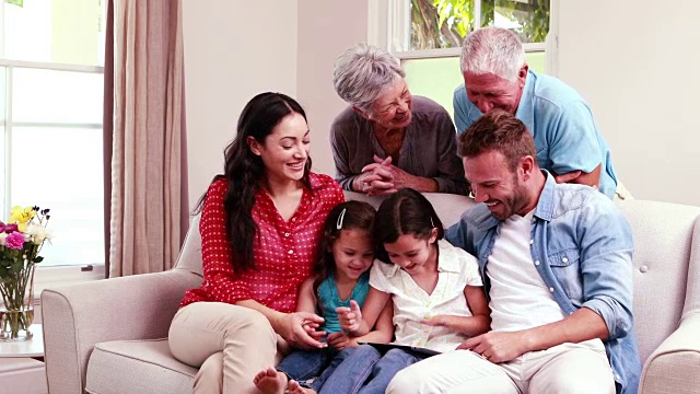 微笑的家人在沙发上使用平板电脑视频下载