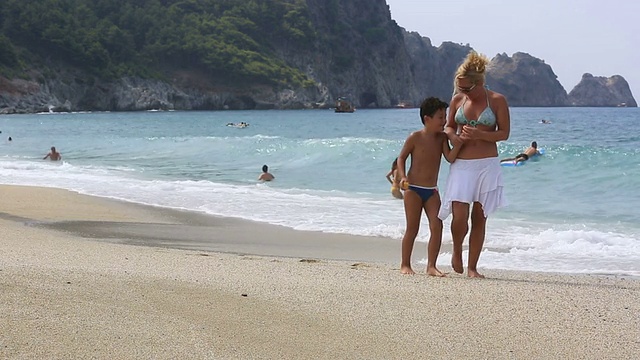 妈妈和儿子在海滩上散步视频素材