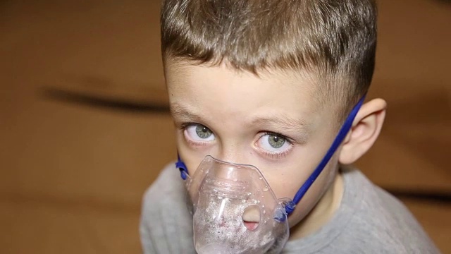 一个寒冷的男孩用吸入器吸了一口气视频下载