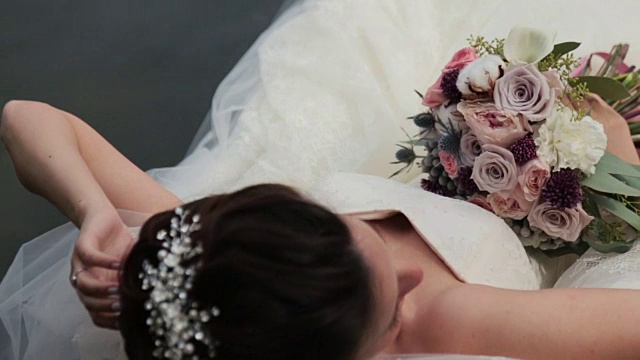 美丽的新娘手捧鲜花躺在俯视图视频下载
