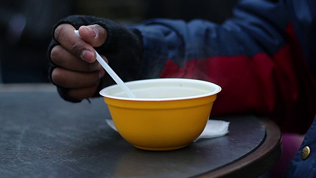 饥饿的穷人贪婪地吃着塑料碗里的热汤视频素材