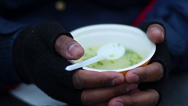 可怜的乞丐用一碗热汤暖着冰冷的手，视频素材